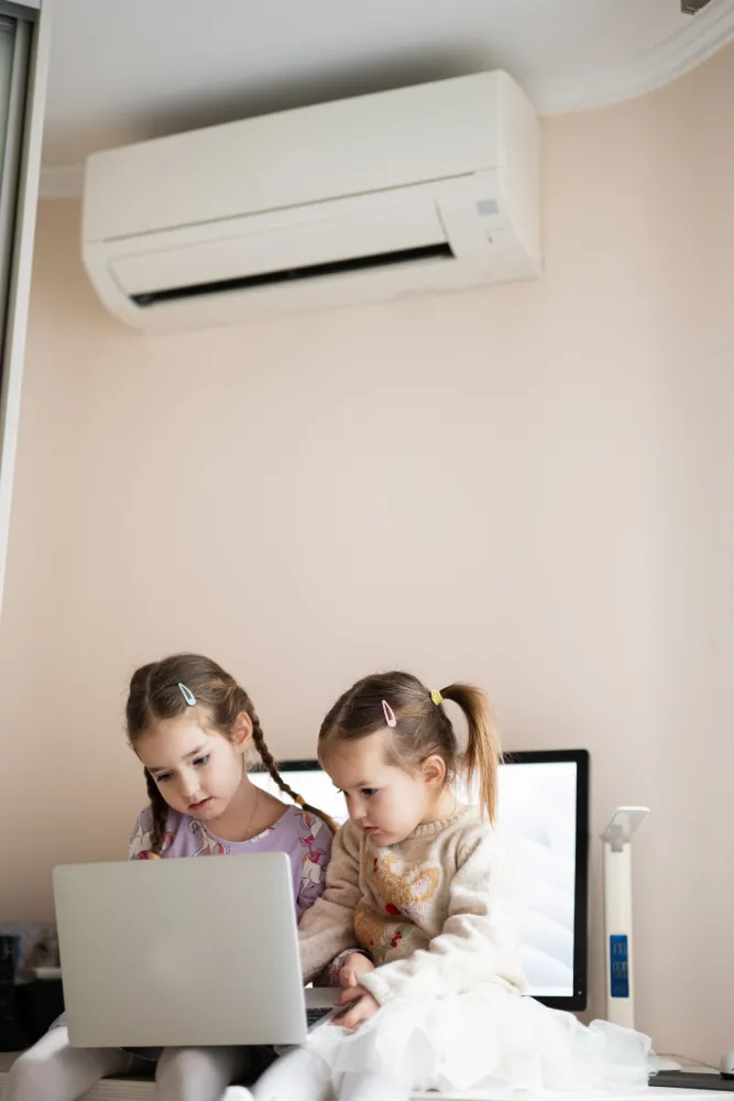 Two girls sitting below aircon